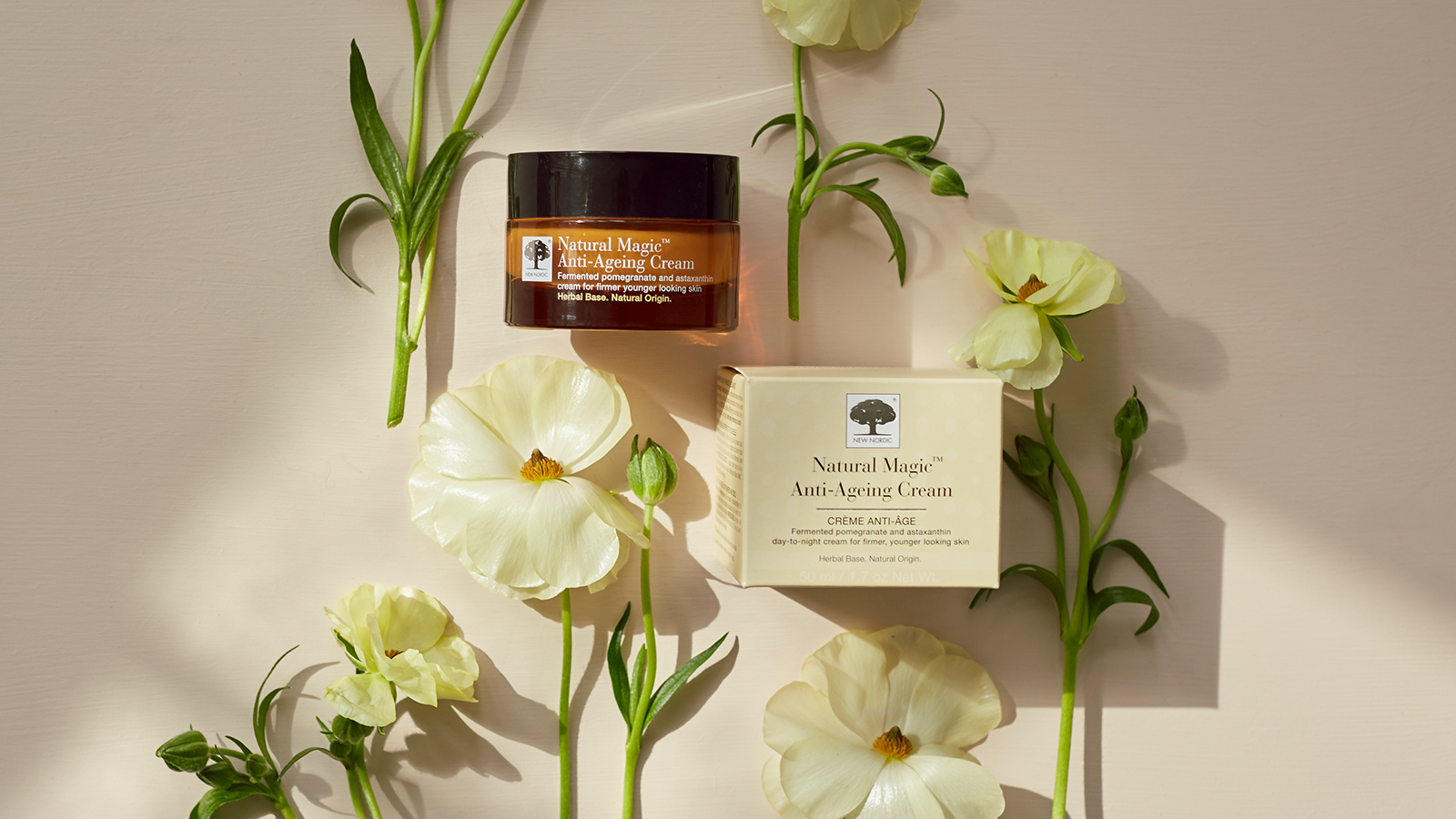 Sig farvel til tørhed og fine linjer – sådan virker Natural Magic™ Anti-Ageing Cream 10 Natural Magic™ Anti-Ageing Cream med krukke og æske omgivet af lyse blomster på lys baggrund.