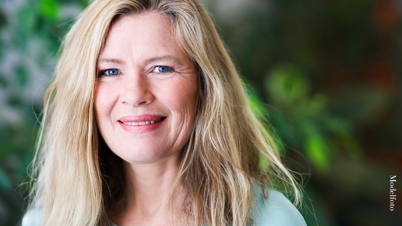 “Jeg drømte om at gøre noget ved min bekymringsrynke” 2 Smilende kvinde med lyst hår ser direkte ind i kameraet foran en grøn baggrund.